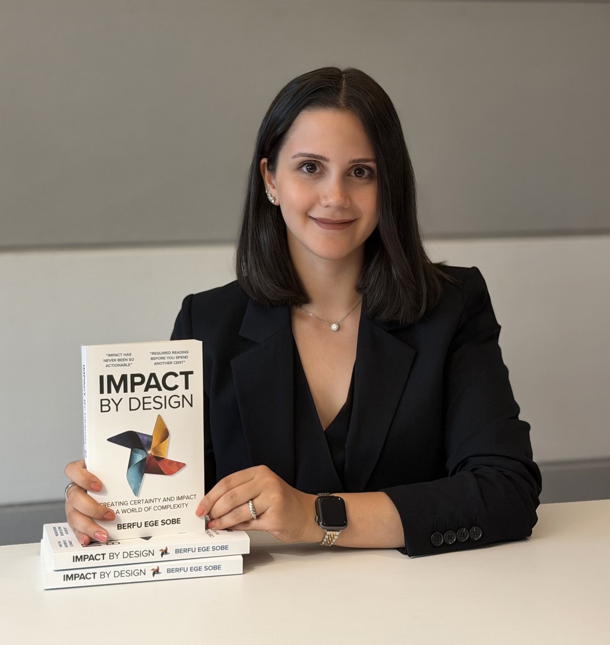 Berfu Ege Sobe holding her book Impact by Design